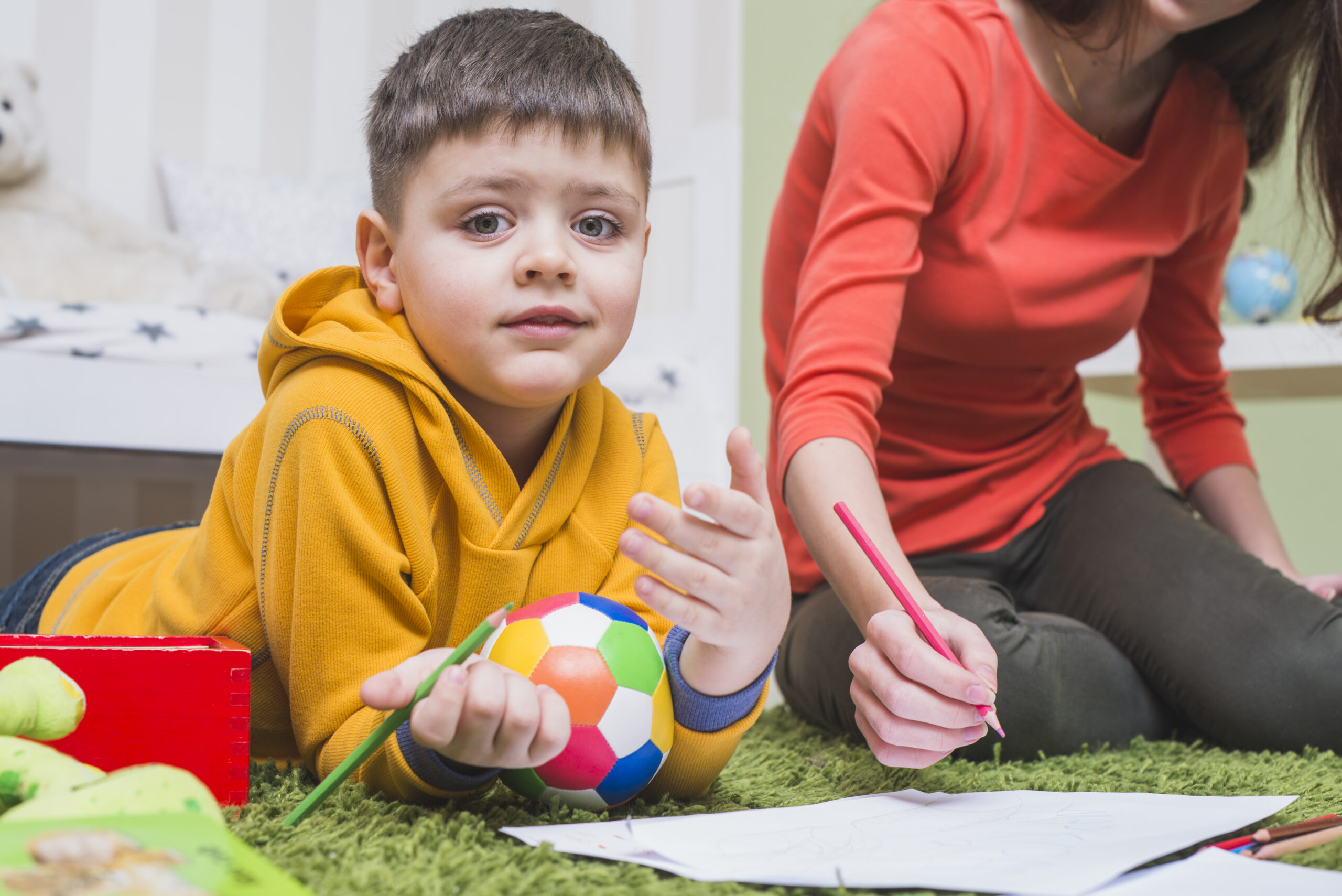 A boy drawing with colored pencils during art therapy.