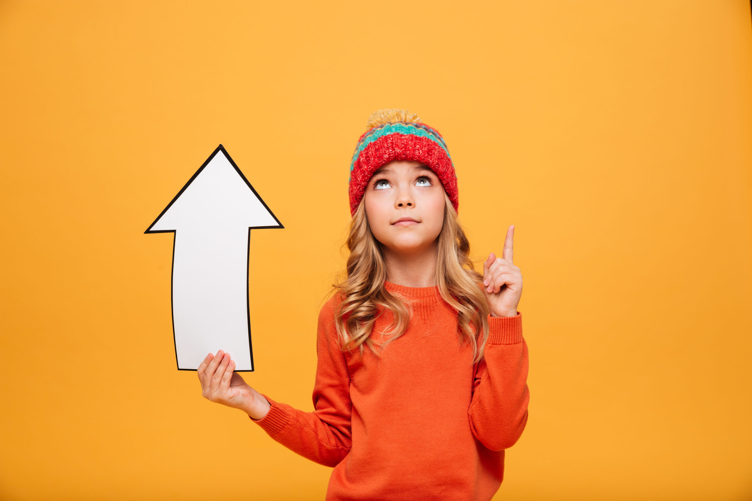 Young girl pointing upwards with a paper arrow, symbolizing progress